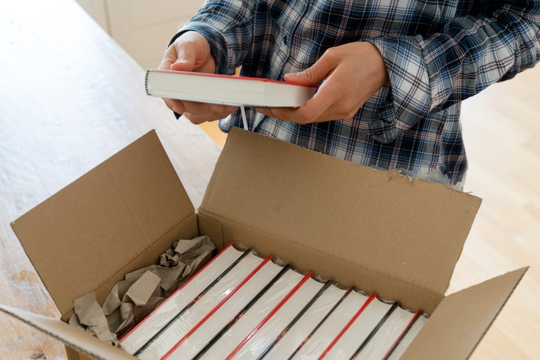 hands-holding-book-over-open-box-of-books