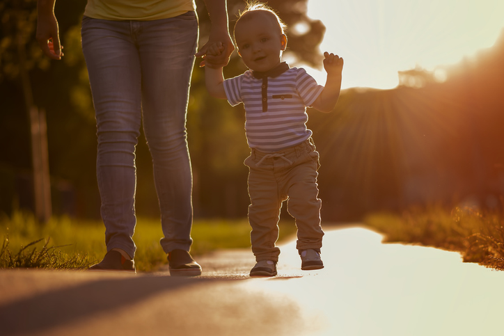 toddler walking with adult outdoors