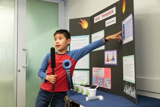 young boy pointing to science experiment